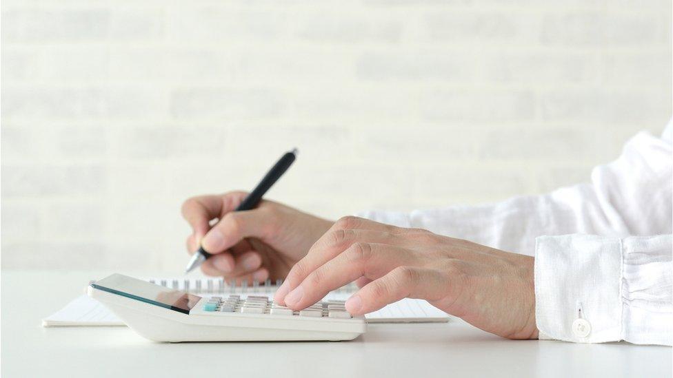 Woman using calculator in living room