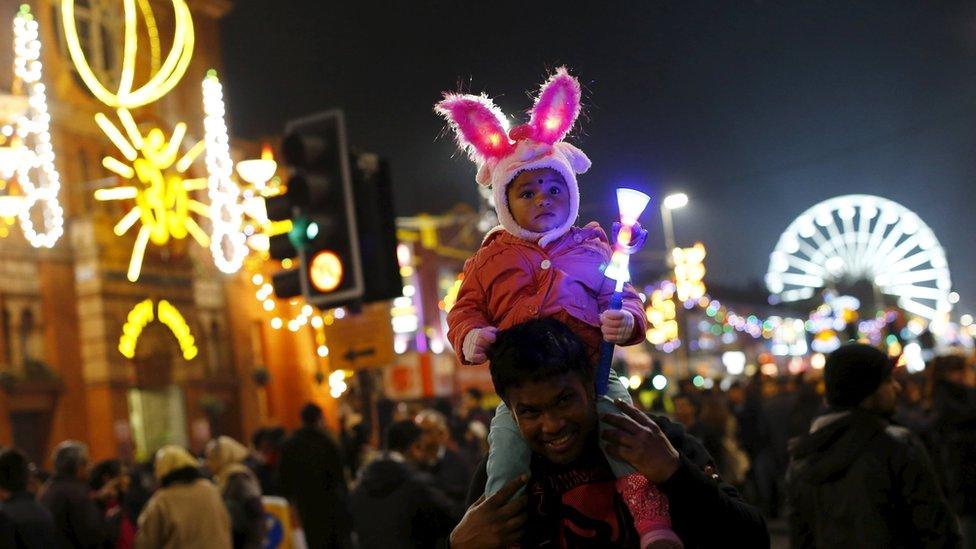 A girl sits on her father"s shoulders after the switching on of Diwali lights in Leicester