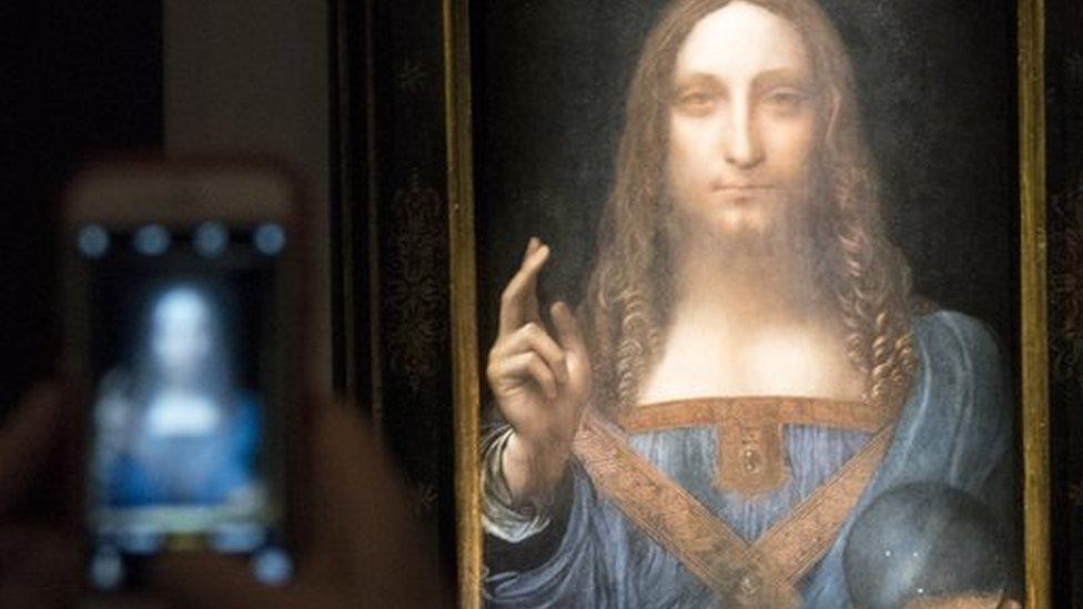 Someone takes a smart phone image of the painting in a darkly lit room