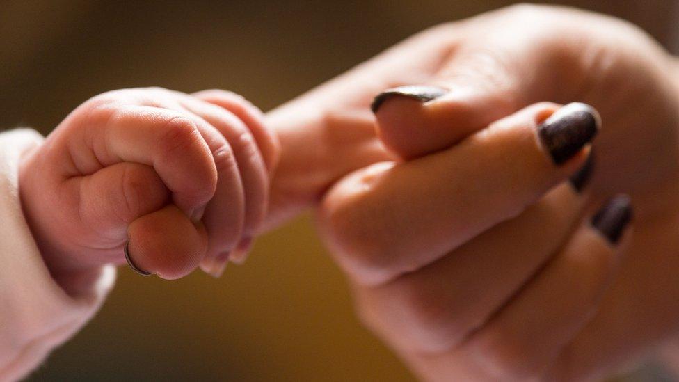 Baby holding mum's finger