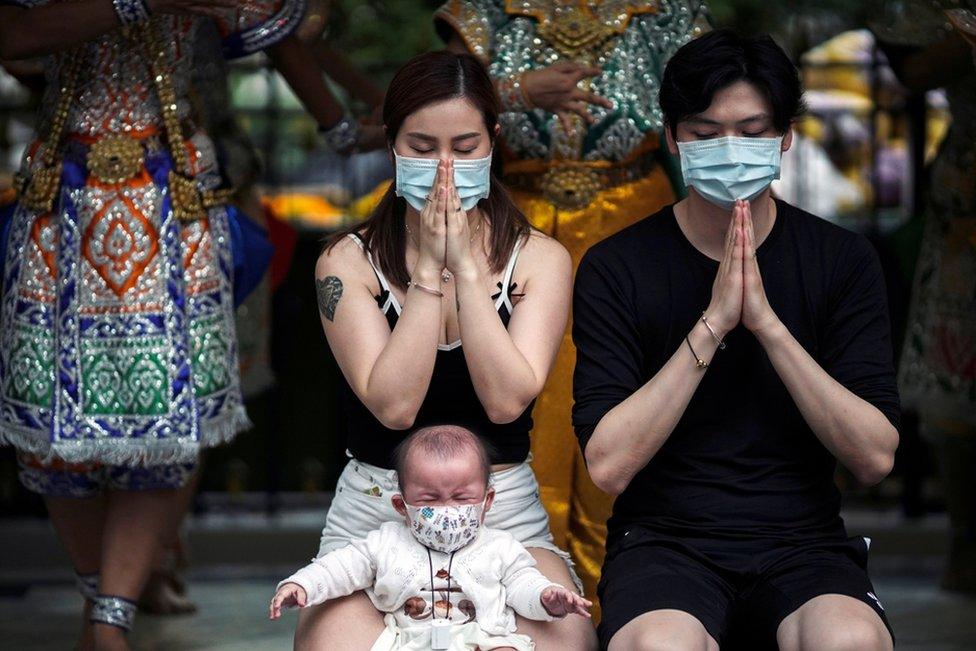 Chinese tourists wearing protective masks pray at the Erawan Shrine in Bangkok, Thailand.