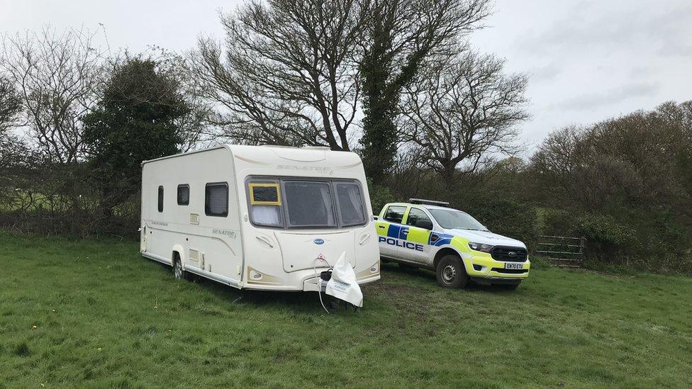 A caravan and a police car in a field