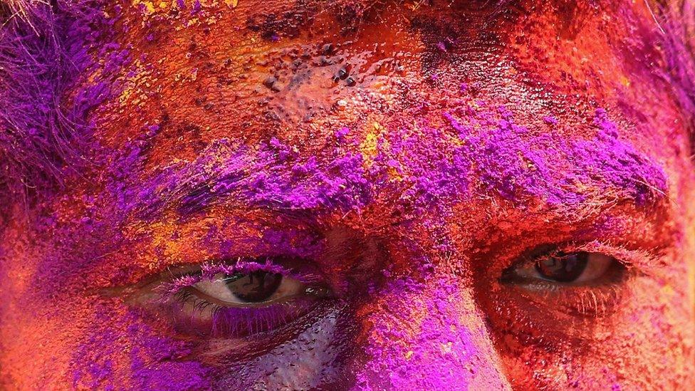 A close-up of a face covered in coloured paint powder