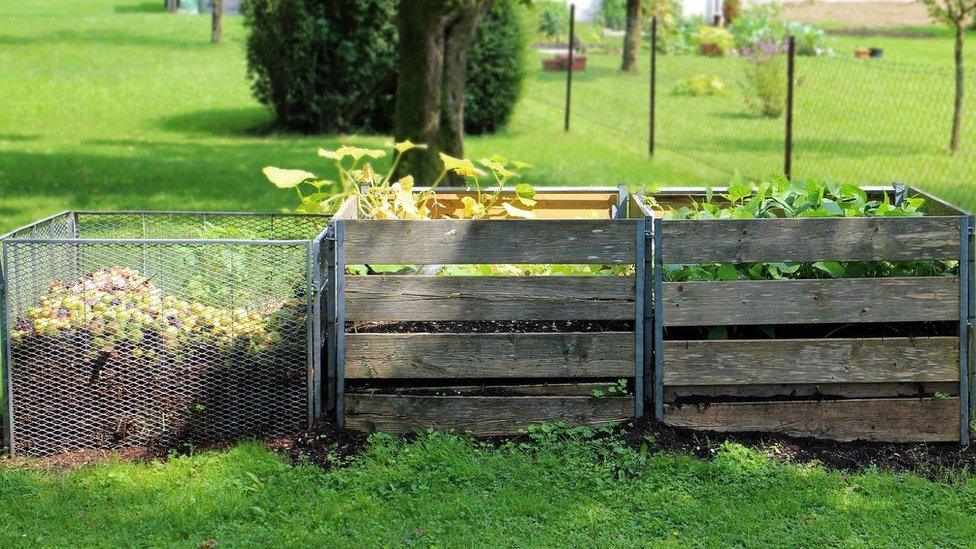 Three composting heaps next to each other in a park setting.