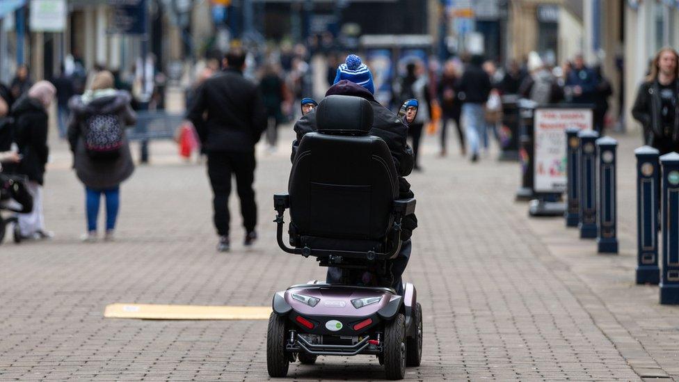 Person riding mobility scooter in public