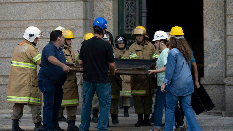 Museum staff and firefighters take a painting from the debris of Rio de Janeiro's National Museum on September 3, 2018