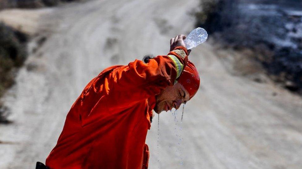 A member of the Prado fire crew pours water over his head to cool off