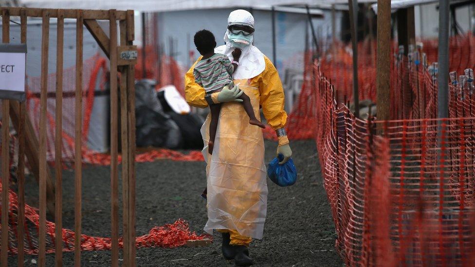 MSF health worker carries a child