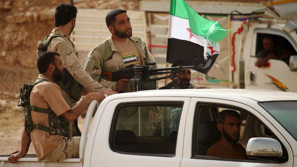 Syrian rebel fighters stand in the back of a pick-up truck during a military parade in the southern city of Deraa on 7 June 2018