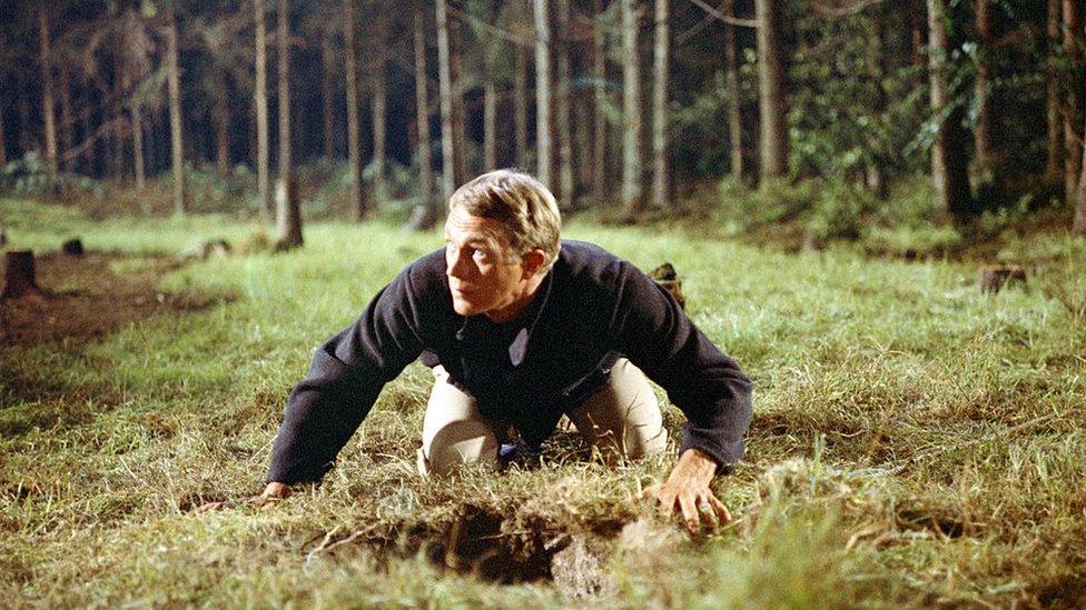 Steve McQueen emerges from a tunnel in The Great Escape