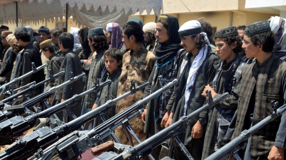 A line of IS members in front of weapons