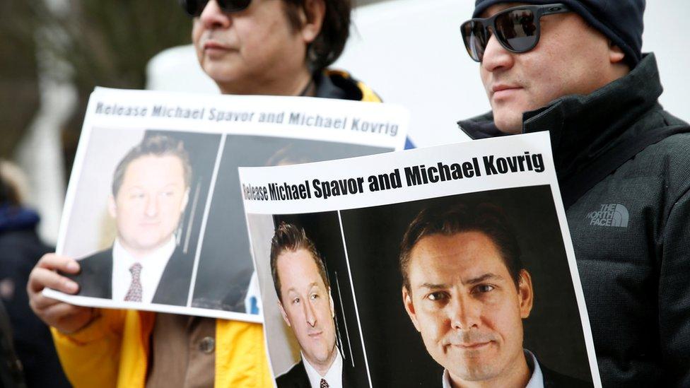 People hold signs calling for China to release detainees Michael Spavor and Michael Kovrig during an extradition hearing for Meng Wanzhou