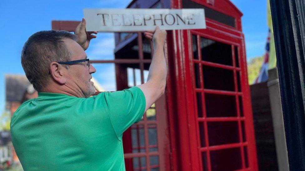 David Lewis adding the "telephone" sign to the telephone box in Mickleover