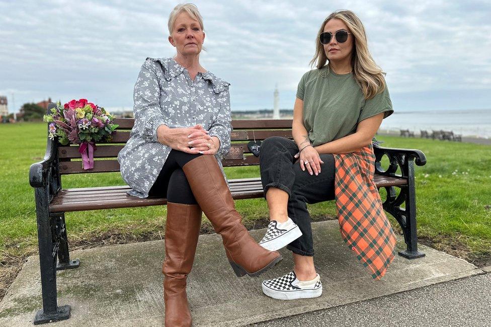 Two women sit on a bench