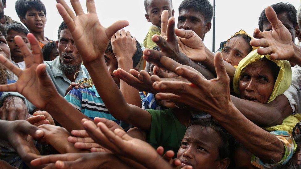 This 30 August 2017 photo shows Rohingya refugees reaching for food aid at Kutupalong refugee camp in Ukhiya near the Bangladesh-Myanmar border