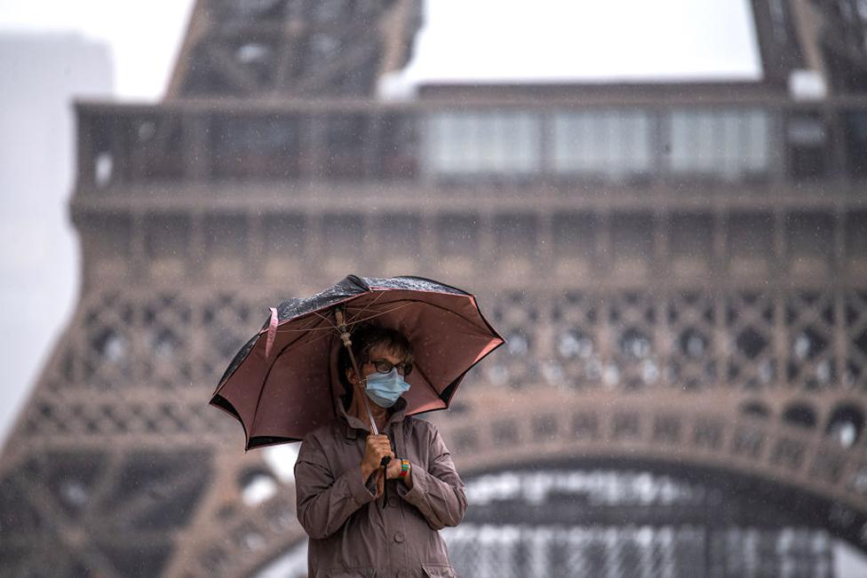 man in face mask in front of Eiffel tower