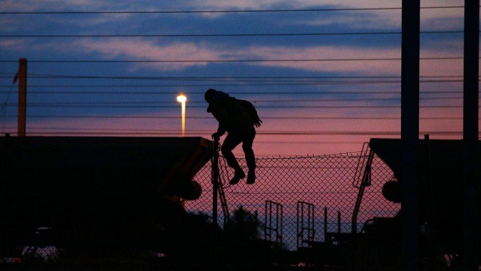 A migrant climbs onto a train in Coquelles, Calais