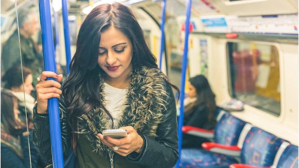 Woman using her mobile phone on an underground train