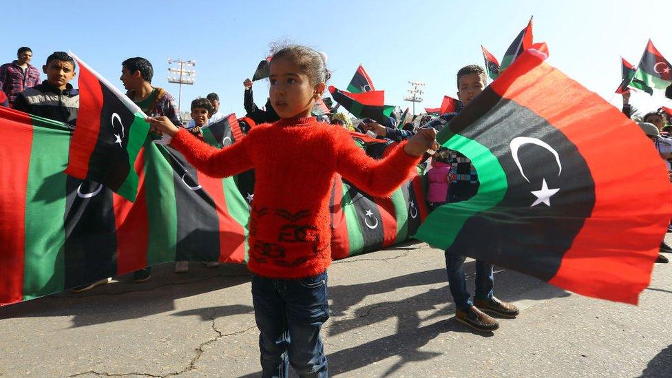 A Libyan girl waves her country's national flag as she takes part in a celebration marking the sixth anniversary of the Libyan revolution, which toppled strongman Moamer Kadhafi, at the Martyrs' Square in the capital Tripoli, on February 17, 2017.