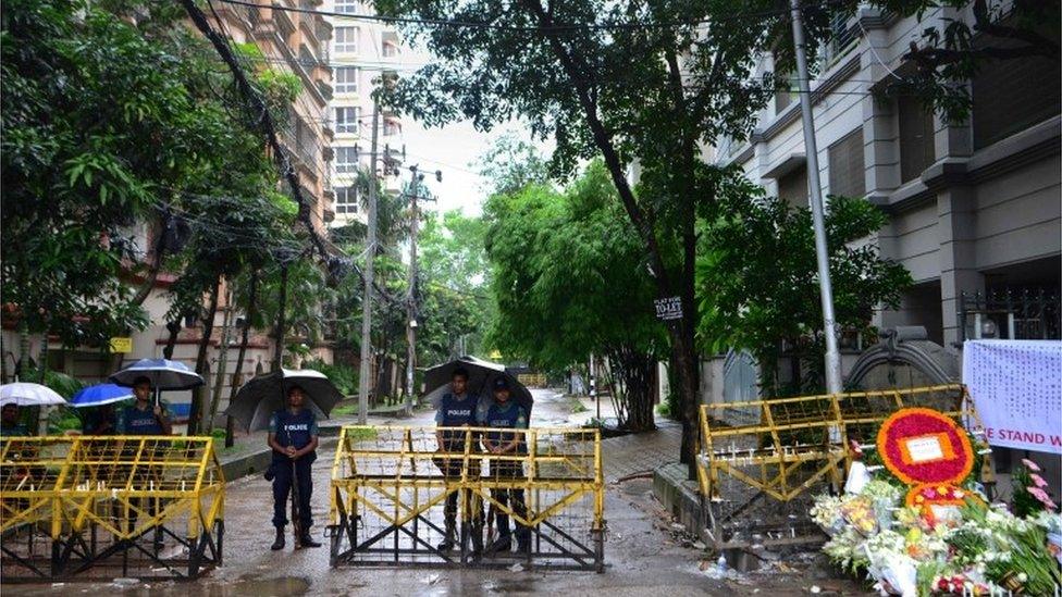 Bangladeshi policemen stand under umbrellas at a checkpoint in Dhaka