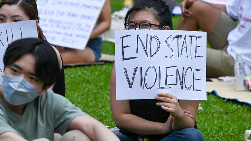 Attendees hold signs during a protest against the death penalty at Speakers' Corner in Singapore on April 3, 2022.