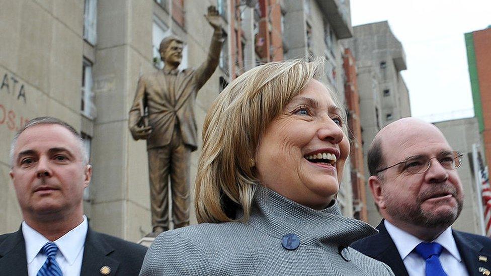 US Secretary of State Hillary Clinton poses in front of a statue of her husband, former US president Bill Clinton, during an unannounced stop on a drive from the airport to Pristina on 13 October 2010