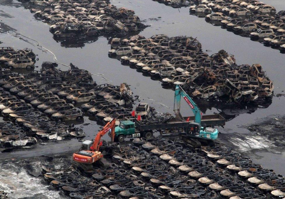 This picture taken on 20 August 2015 shows rescuers cleaning up damaged cars during the explosions in Tianjin