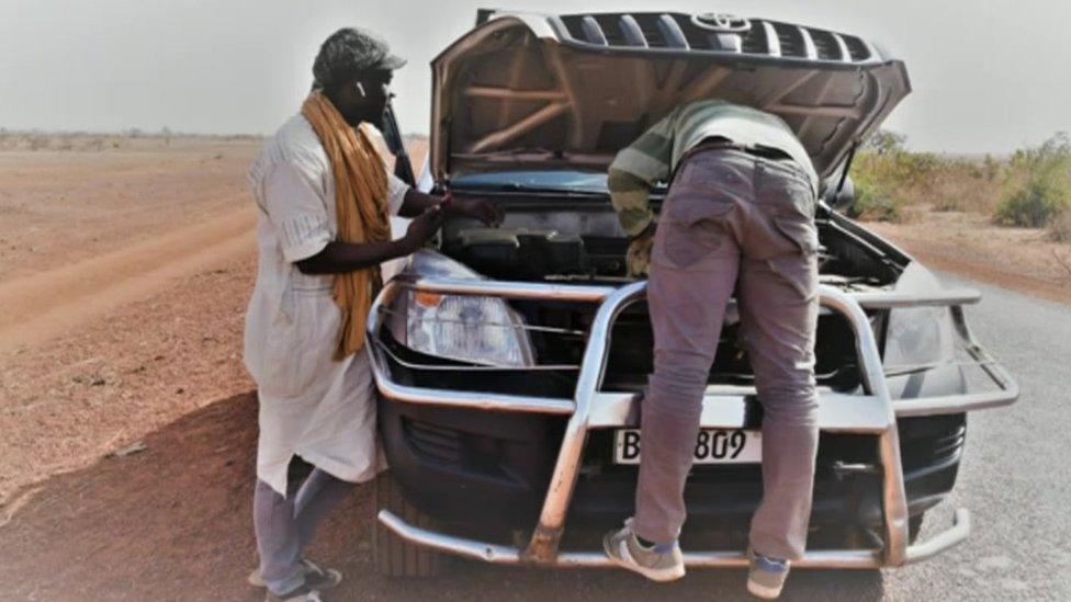 A car broken down by the side of a road in Africa