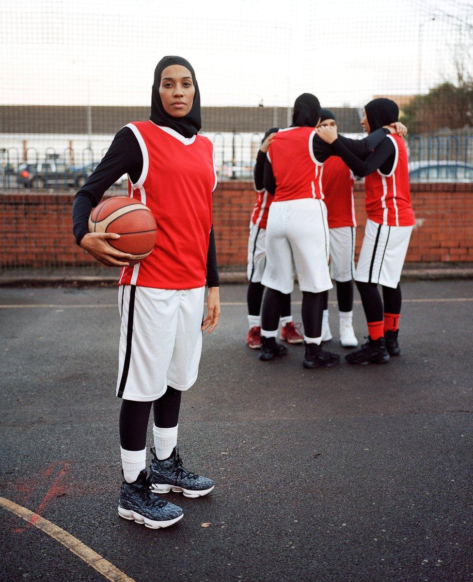 Portrait of Asma standing on a basketball court with her teammates behind her