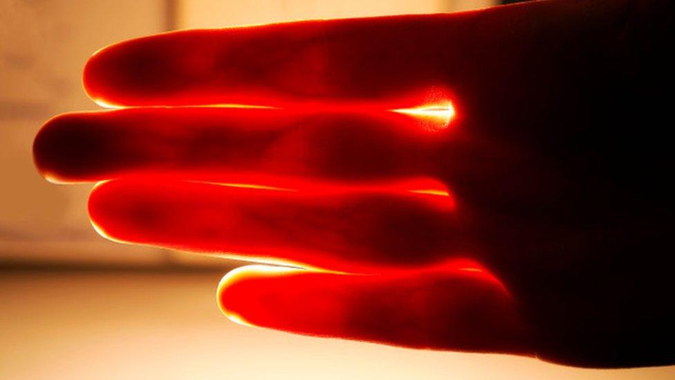 Red light shining through a person' hand