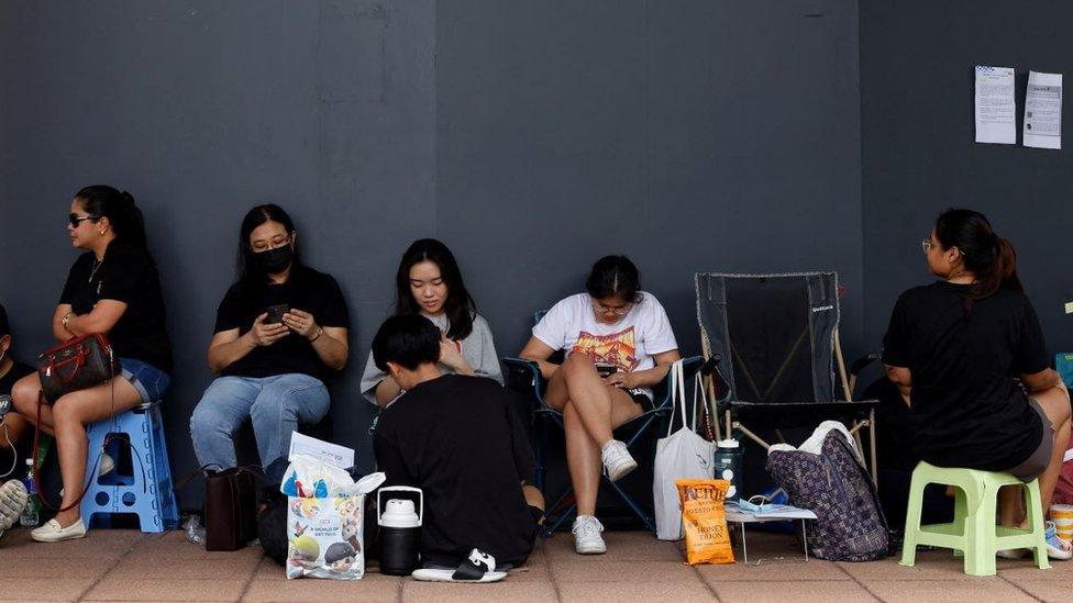 People sit down in an hours-long queue outside a Singapore post office in a bid to secure tickets to Taylor Swift concerts