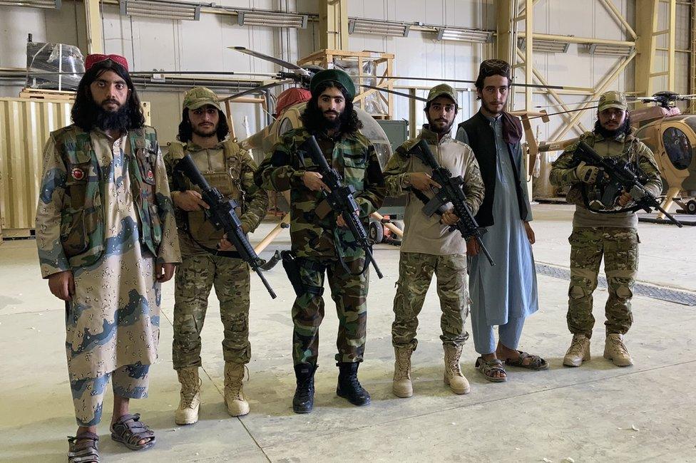 Taliban fighters pose in front of former army helicopters at Balkh airfield.