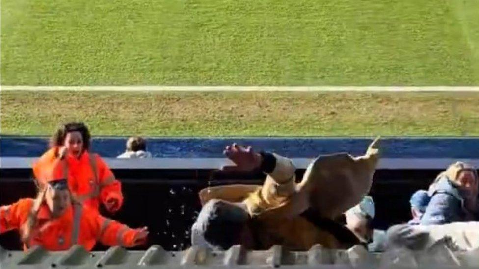 Man falling off sloped roof as two stewards look on