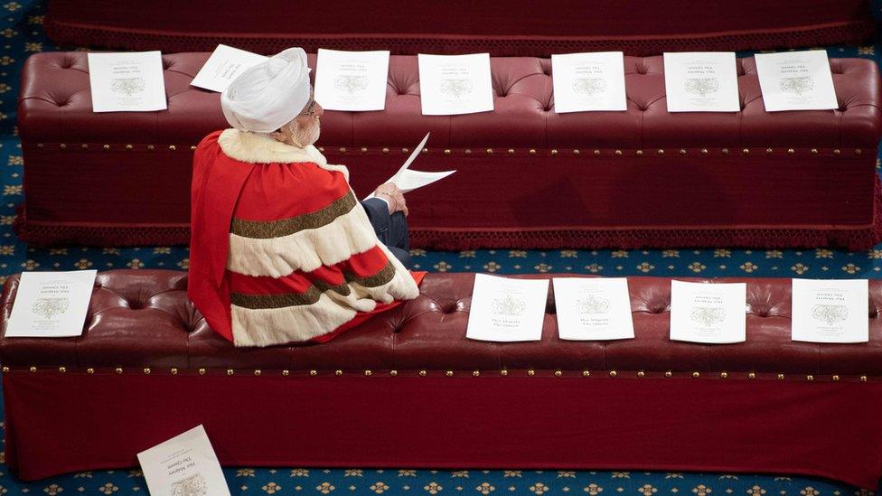 A member of the House of Lords sits on a bench in the House of Lords