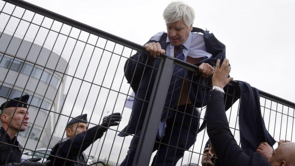 Director of Air France in Orly Pierre Plissonnier, nearly shirtless, tries to cross a fence, helped by security and police officers, after several hundred of employees invaded the offices of Air France