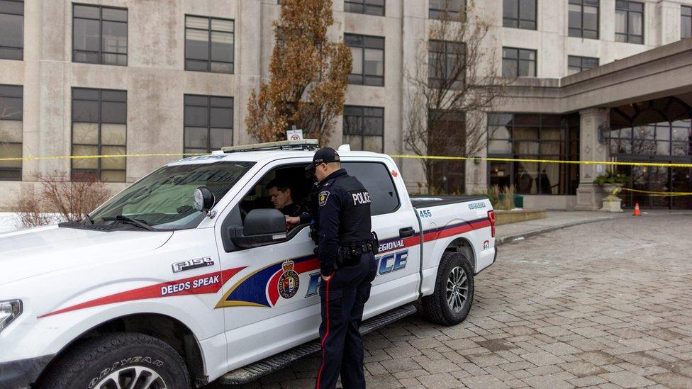 Police officers stand outside the building after a fatal mass shooting in the Toronto suburb of Vaughan