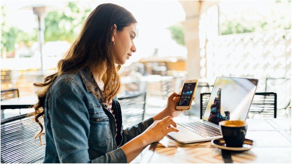 Woman looking at mobile phone and laptop