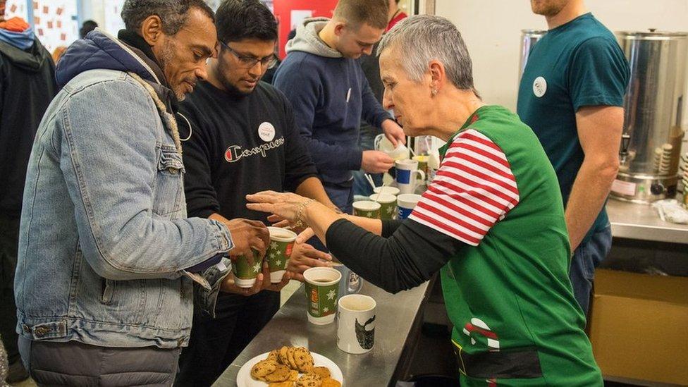 A Crisis volunteer serves coffee to a homeless guest.