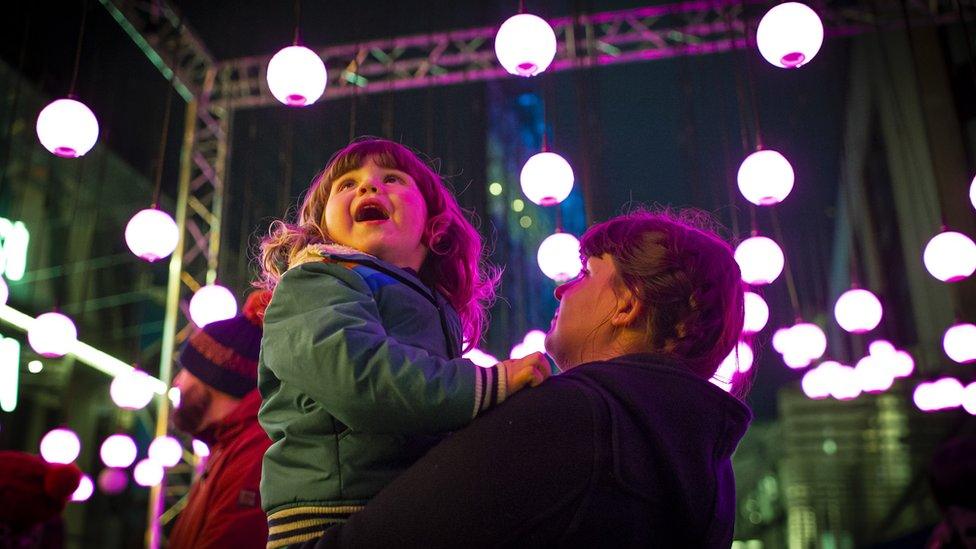 Child in adults arms looking at the lights