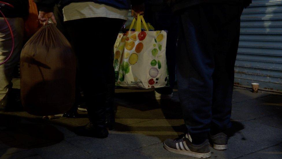 Users of a soup kitchen carrying their belongings in bags for life