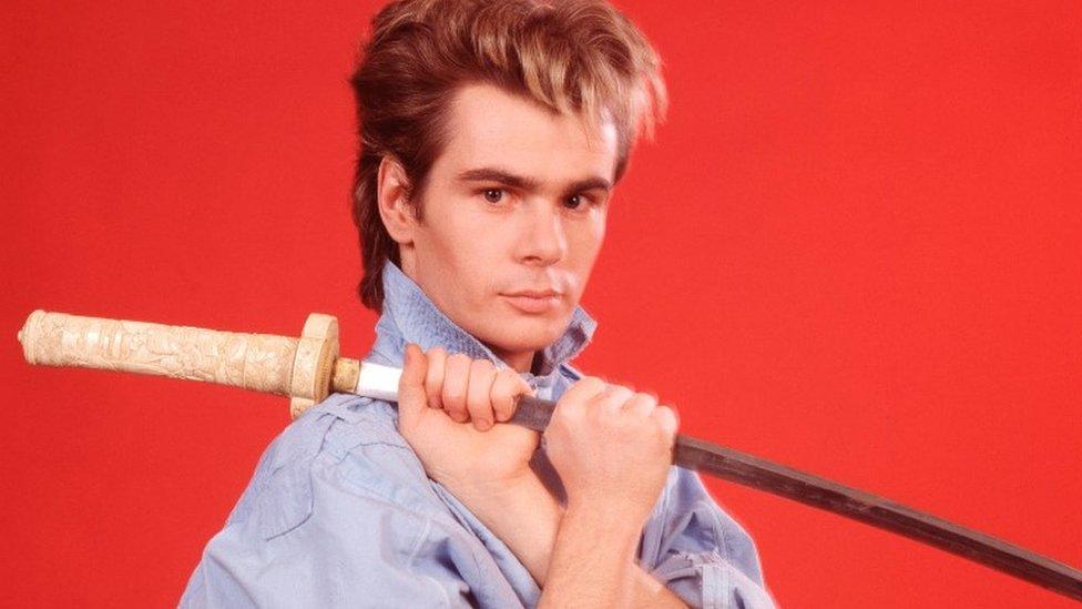 Nik Kershaw, poses with a samurai sword, London, July 1984