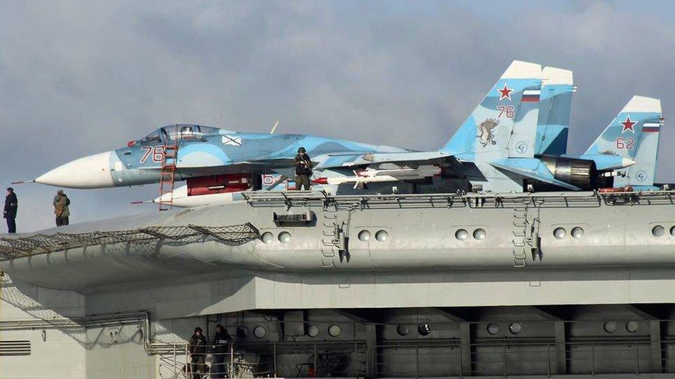 Armed military personnel alongside aircraft on the flight deck of Russian aircraft carrier Admiral Kuznetsov in the English Channel on 21 October