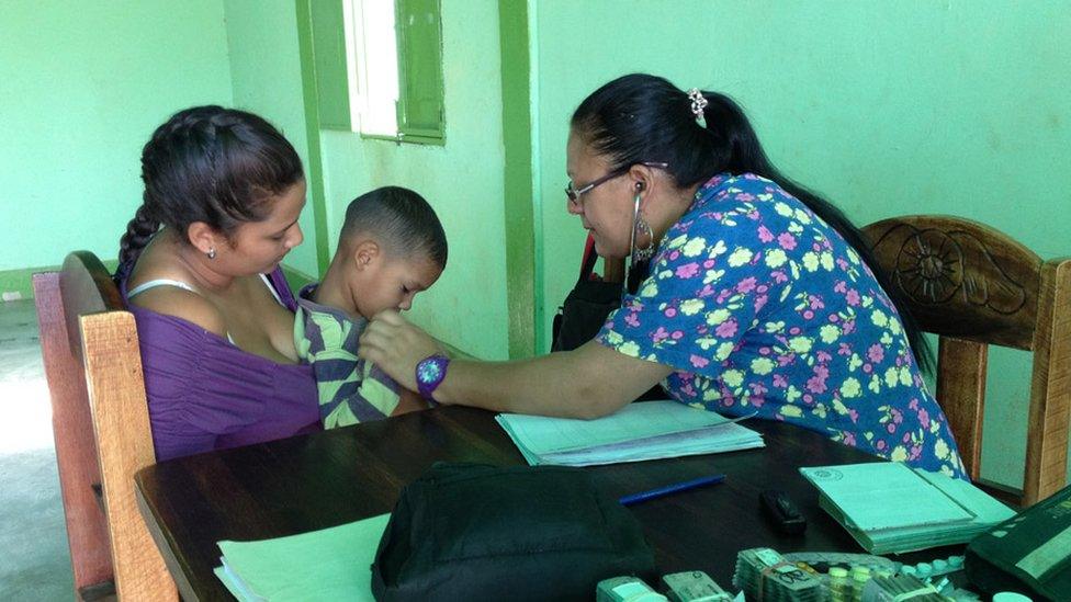 A doctor checks a child on the porch of Maria Torres' home