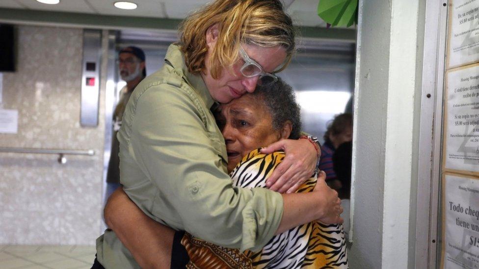 Puerto Rico's mayor holds an upset elderly woman after Hurricane Maria