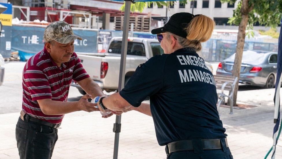 Homeless security worker distributing water