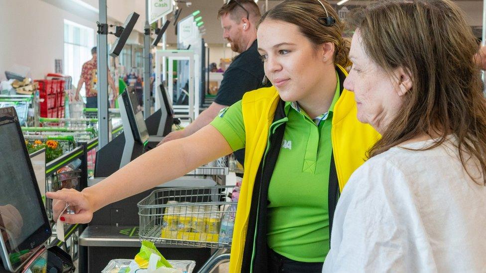 An Asda staff member helps a customer