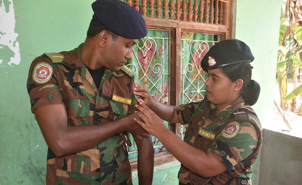 Gauri adjusts a badge on Roshan's uniform