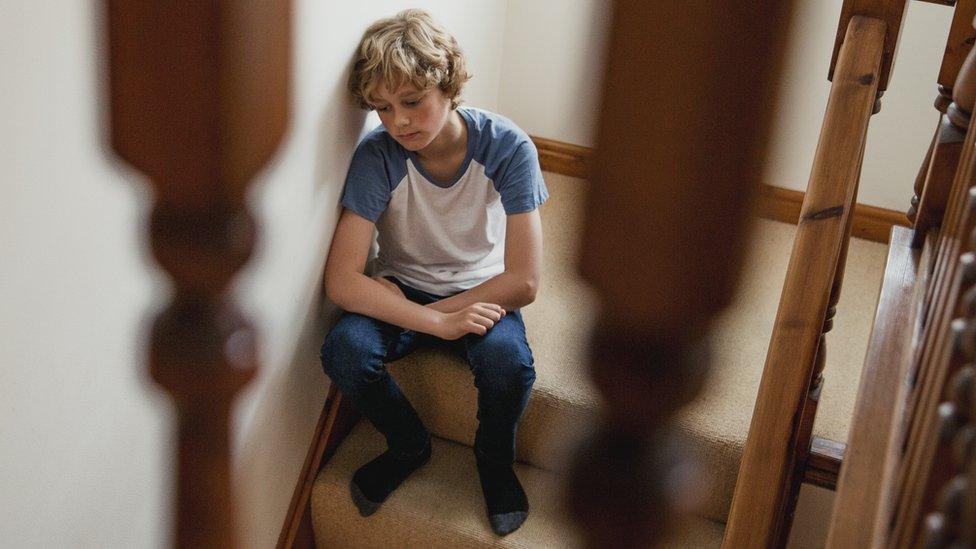 Boy looking sad while sitting on stairs