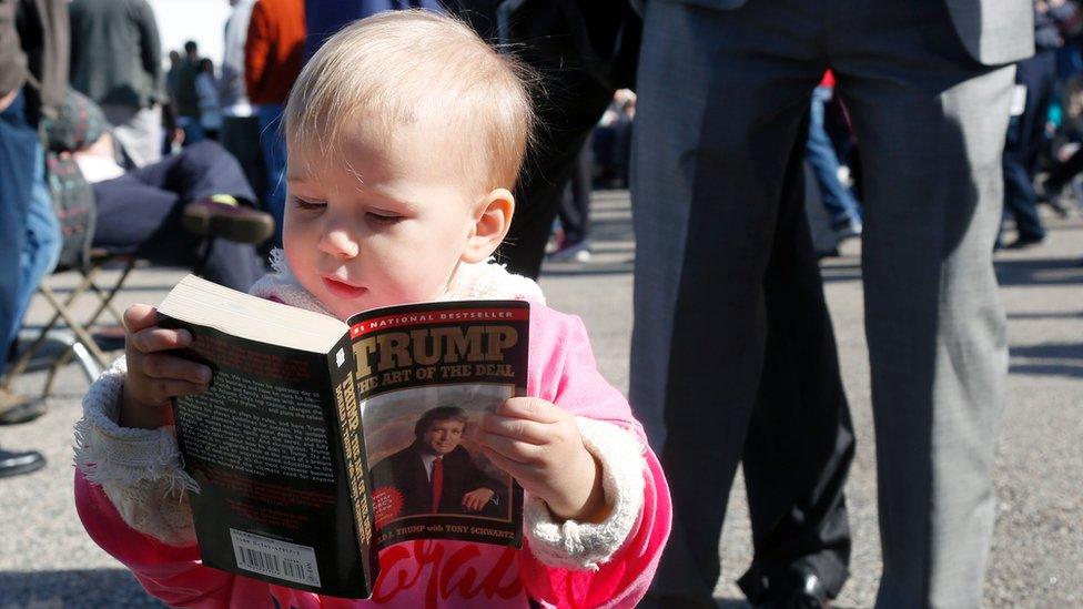 Grace Mahoney, 16 months, looks at a copy of 'The Art of the Deal' before the start of an event with Republican presidential candidate Donald Trump on October 15, 2016 in Portsmouth, New Hampshire.