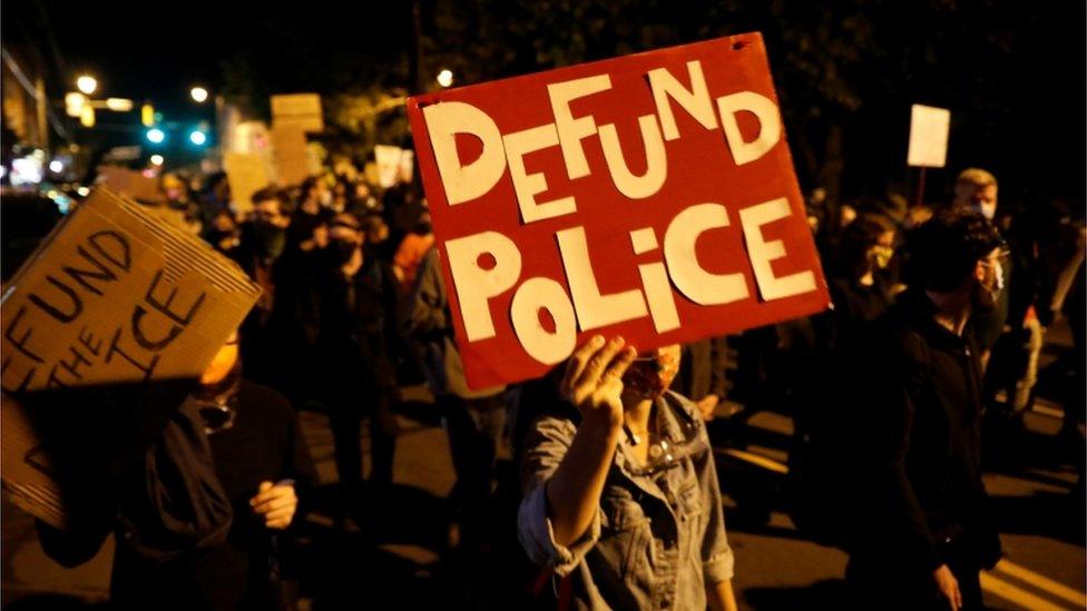 A protester in Rochester holds a sign that reads: 'Defund police'